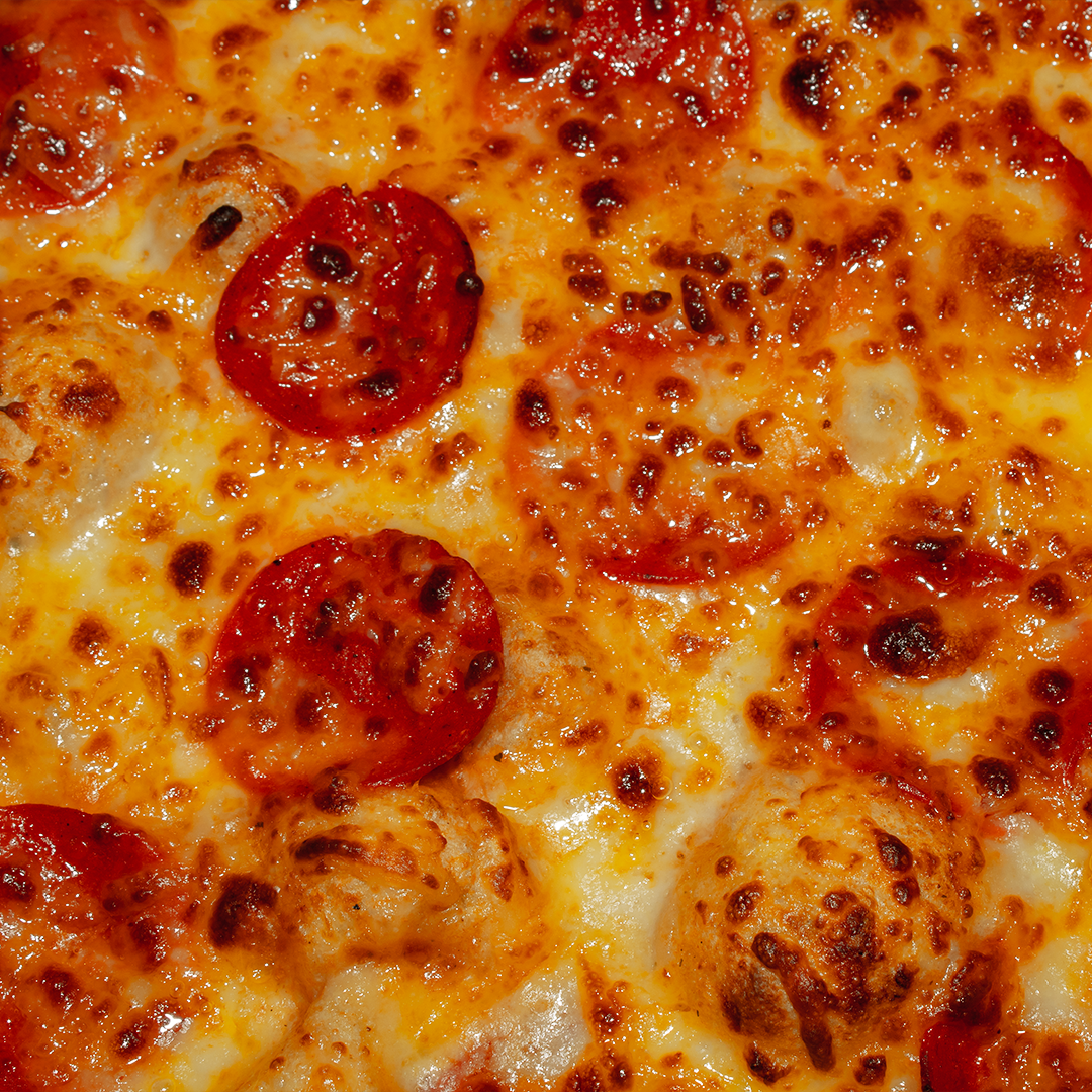 Detalle cerrado del queso y pepperoni de una pizza
